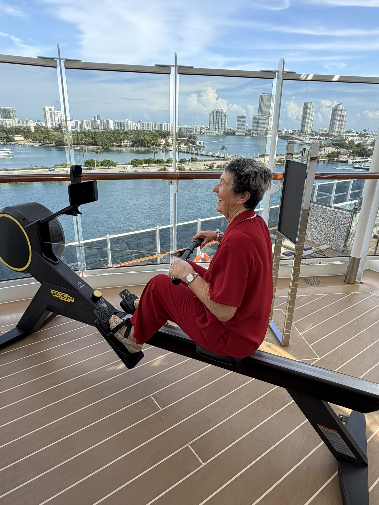 Grandma trying out the rowing machine with a view of Miami