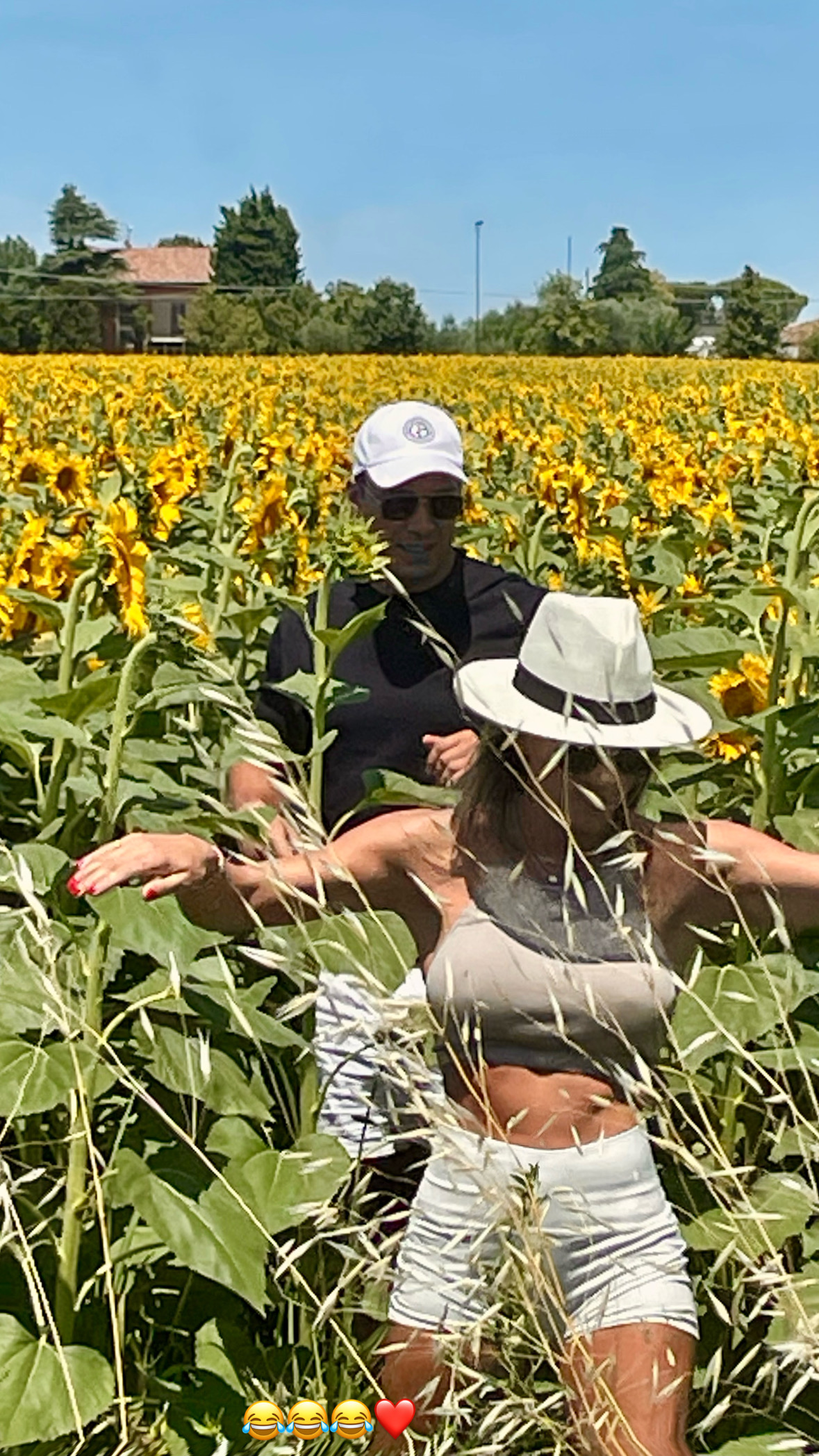 Amanda and Mattia laughing in a sunflower field