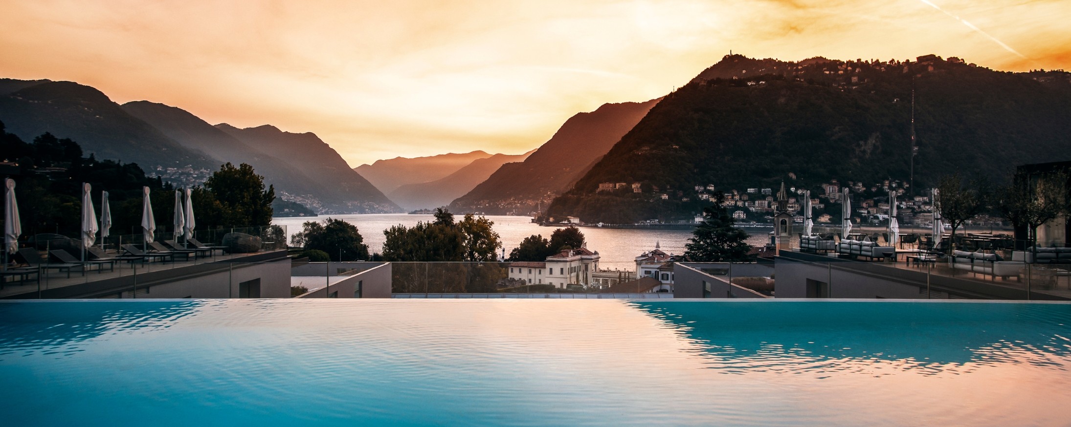 The Hilton Lake Como rooftop infinity pool at sunset, overlooking the lake and surrounding mountains
