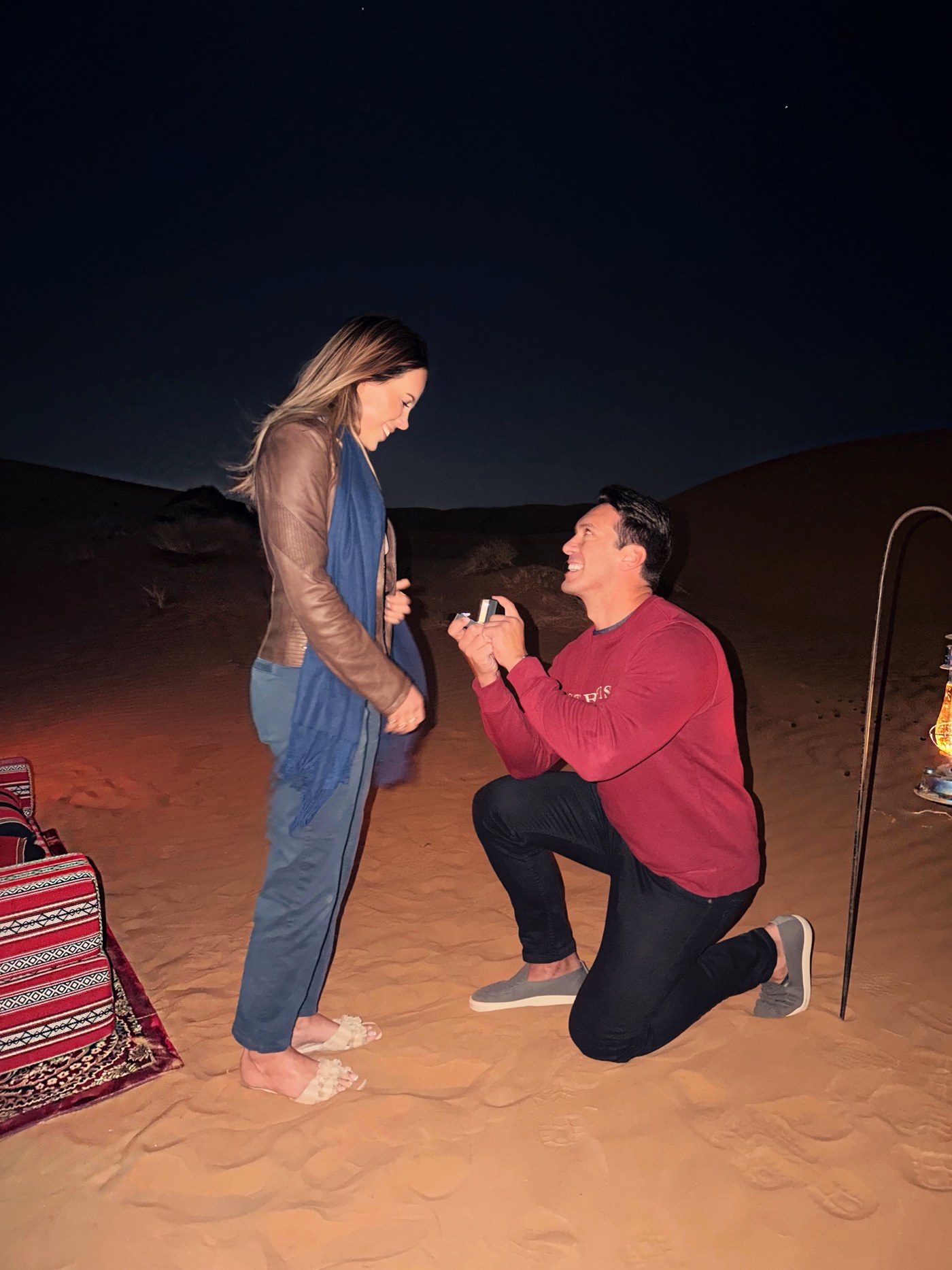Mattia kneeling to propose to Amanda under the night sky in the Wahiba Sands desert, Oman