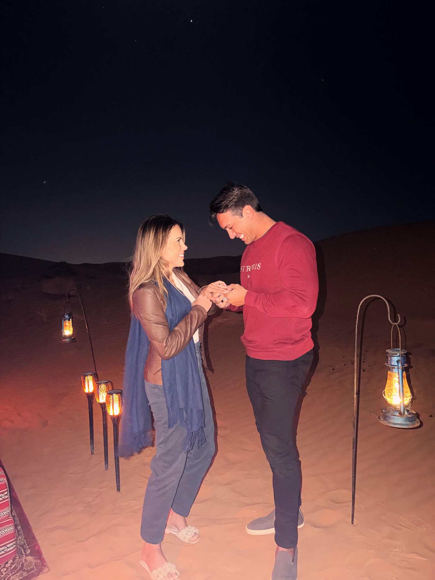 Amanda and Mattia holding hands as he places the ring on her finger in the desert