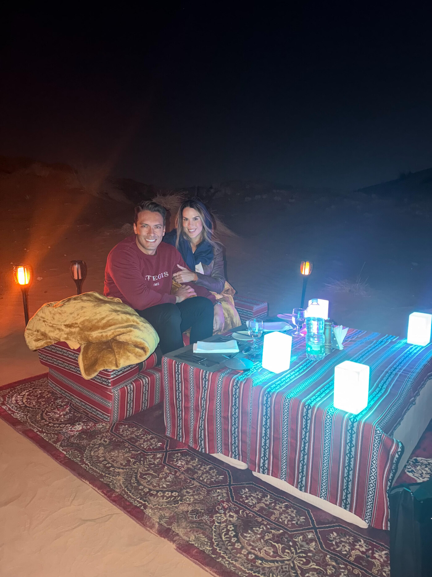 Amanda and Mattia seated together at their candlelit desert dinner table after the proposal